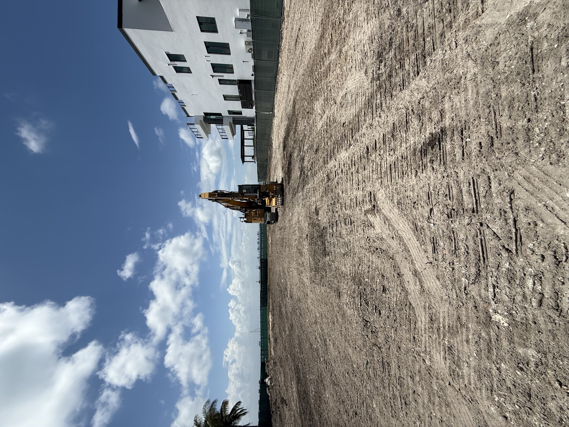 Freshly cleared and graded lot beside a modern building